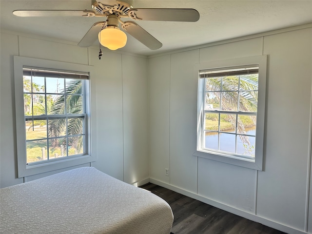 bedroom with ceiling fan, multiple windows, and dark hardwood / wood-style floors