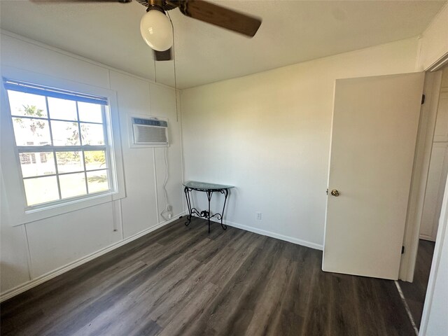 unfurnished room with dark wood-type flooring, a wall unit AC, and ceiling fan