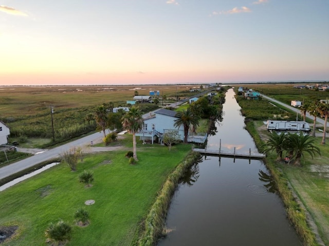 aerial view at dusk featuring a rural view and a water view