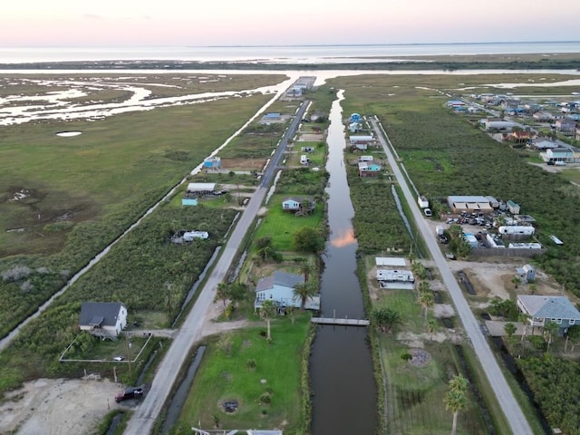 aerial view at dusk featuring a water view