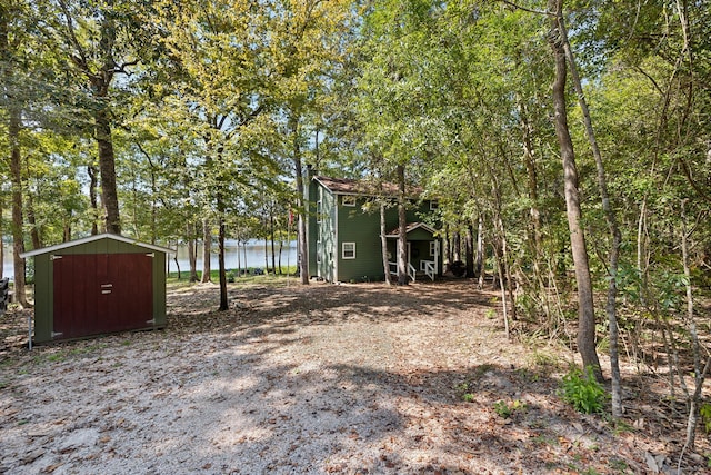 view of yard featuring a storage shed and a water view