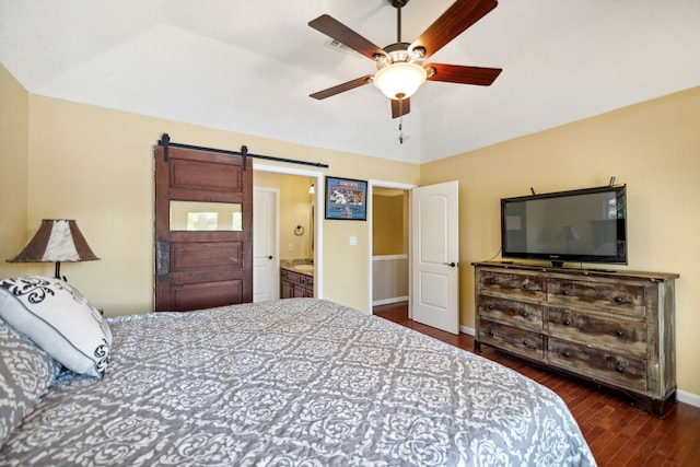 bedroom with dark wood-type flooring, vaulted ceiling, a barn door, ensuite bath, and ceiling fan