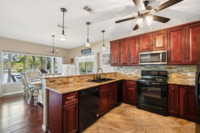 kitchen with sink, kitchen peninsula, a textured ceiling, decorative light fixtures, and black appliances