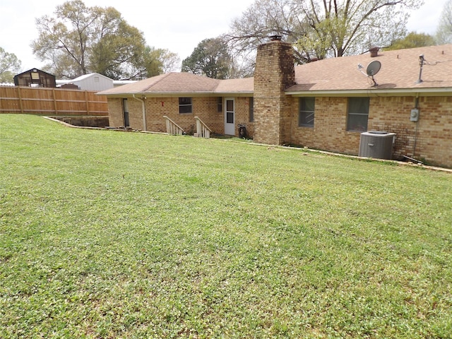 rear view of house with a lawn and central AC