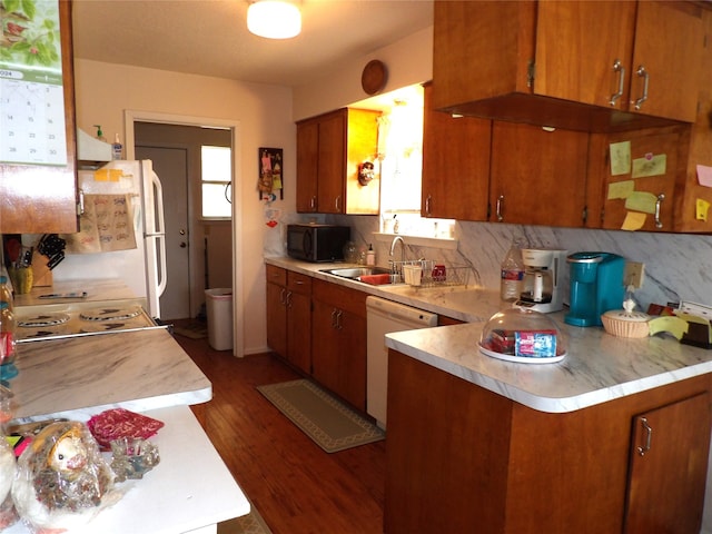 kitchen featuring white appliances, kitchen peninsula, a healthy amount of sunlight, and dark hardwood / wood-style flooring