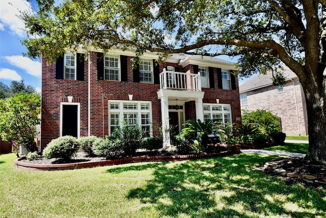 colonial inspired home featuring a balcony and a front yard