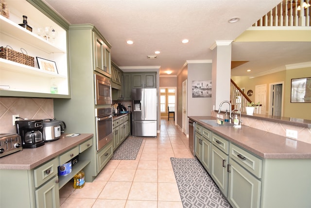 kitchen featuring sink, green cabinets, appliances with stainless steel finishes, light tile patterned floors, and ornamental molding