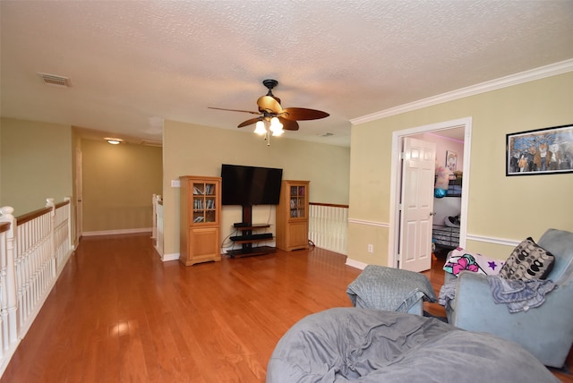 living room featuring ceiling fan, crown molding, hardwood / wood-style floors, and a textured ceiling