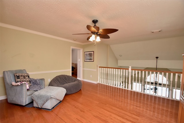 living area featuring ceiling fan, lofted ceiling, wood-type flooring, a textured ceiling, and crown molding