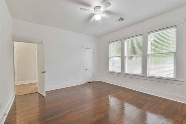 unfurnished room with ceiling fan, dark wood-type flooring, and a wealth of natural light