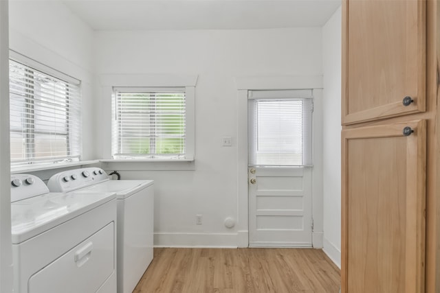 clothes washing area with light hardwood / wood-style flooring, washing machine and clothes dryer, and cabinets