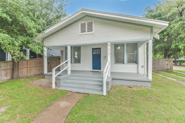 bungalow-style home with a front yard and covered porch