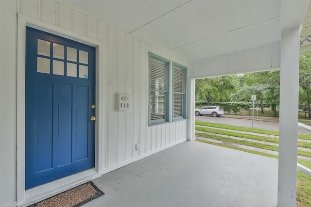 doorway to property with a lawn and a porch