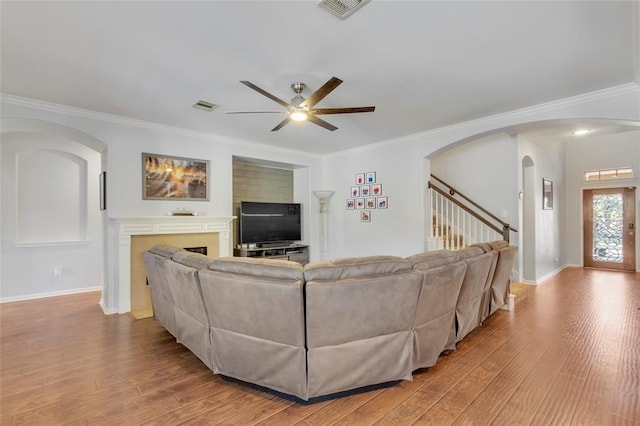 living room with light wood-type flooring, ornamental molding, and ceiling fan