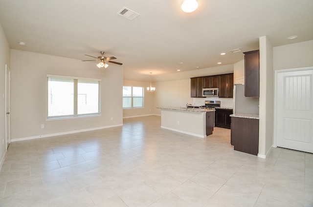 kitchen with ceiling fan with notable chandelier, light tile patterned flooring, appliances with stainless steel finishes, and dark brown cabinetry