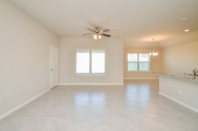 tiled empty room with ceiling fan with notable chandelier