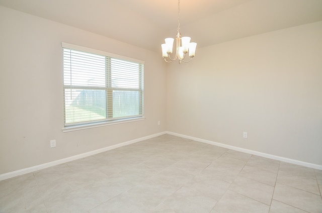 tiled spare room featuring a notable chandelier