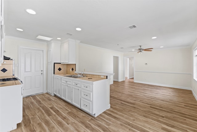 kitchen with white cabinets, light hardwood / wood-style floors, ceiling fan, and sink