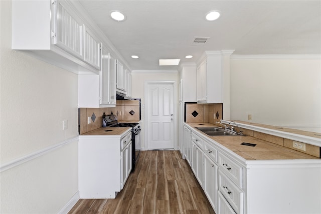 kitchen with black gas stove, sink, white cabinetry, crown molding, and dark hardwood / wood-style flooring