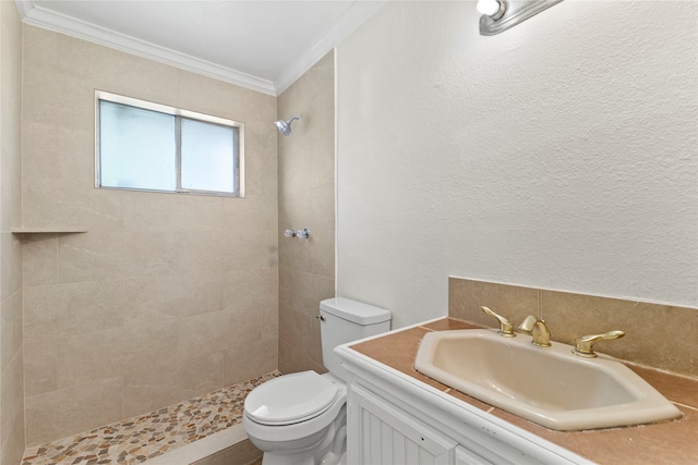 bathroom featuring a tile shower, vanity, crown molding, and toilet