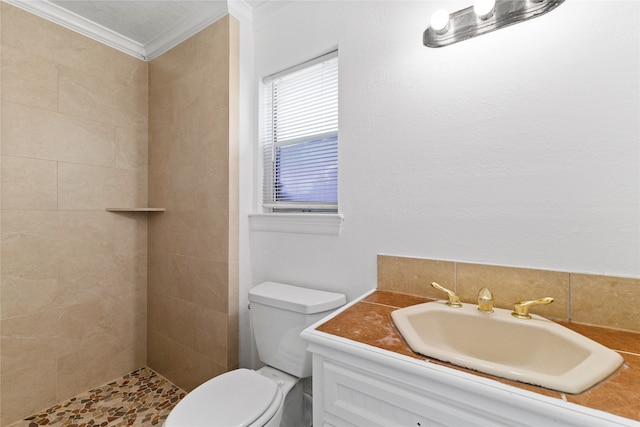 bathroom featuring ornamental molding, tiled shower, vanity, and toilet