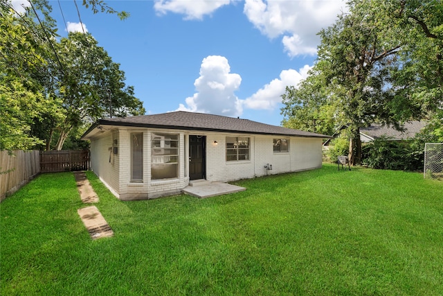 rear view of property with a lawn and a patio