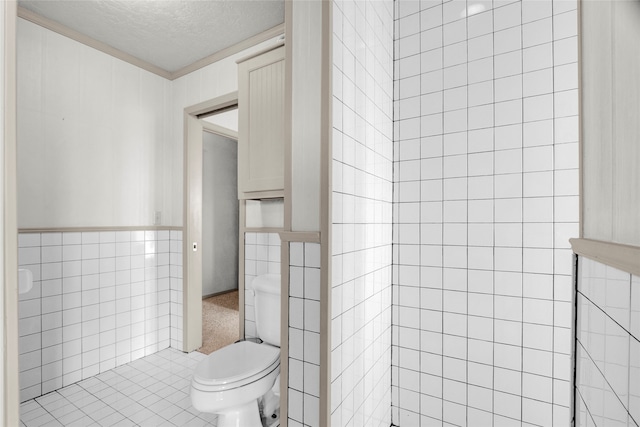 bathroom with a textured ceiling, tile walls, and toilet