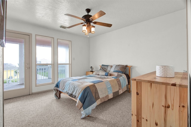 carpeted bedroom featuring a textured ceiling, access to exterior, and ceiling fan