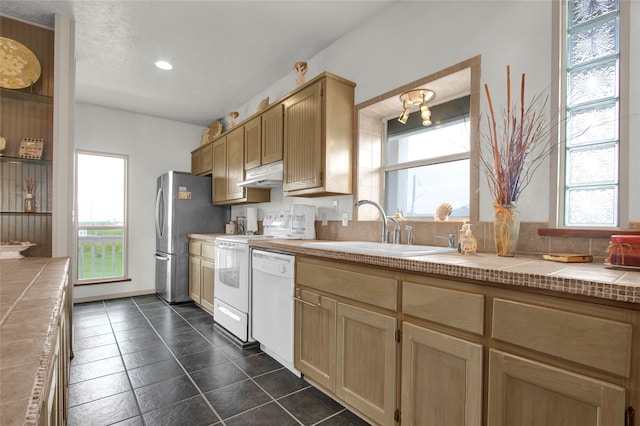 kitchen featuring sink, plenty of natural light, tile counters, and white appliances