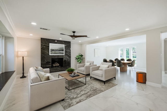 living room featuring ornamental molding, a high end fireplace, and ceiling fan