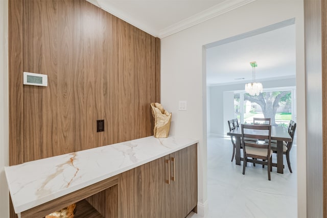 kitchen with a notable chandelier, crown molding, hanging light fixtures, and light stone countertops