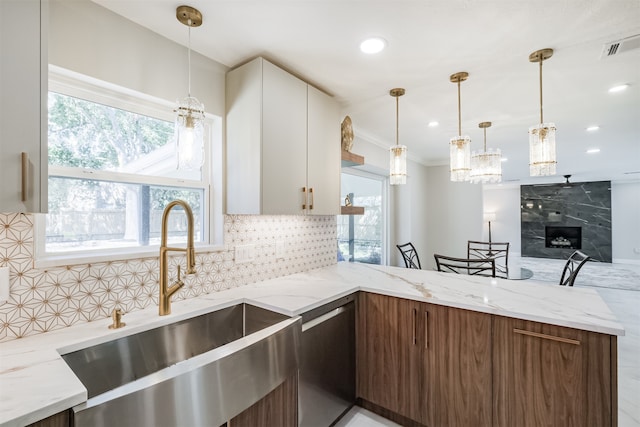 kitchen featuring white cabinets, backsplash, dishwasher, a fireplace, and light stone countertops