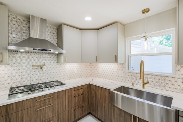 kitchen with wall chimney exhaust hood, decorative light fixtures, backsplash, and white cabinets