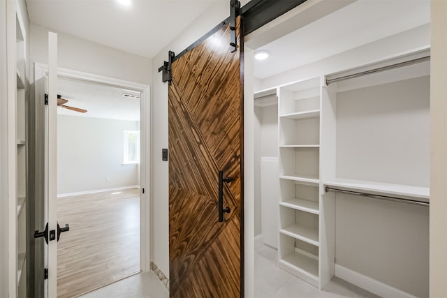 walk in closet with ceiling fan and light hardwood / wood-style flooring