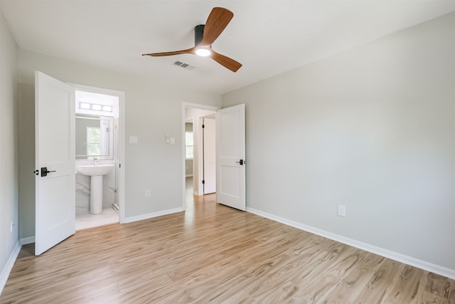 unfurnished bedroom featuring sink, light hardwood / wood-style floors, ensuite bathroom, and ceiling fan