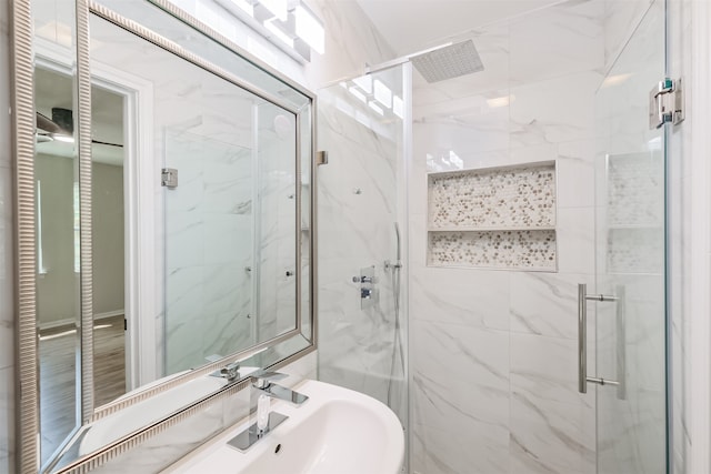 bathroom featuring a shower with shower door and sink