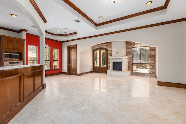 kitchen featuring french doors, a stone fireplace, ornamental molding, a tray ceiling, and stainless steel appliances