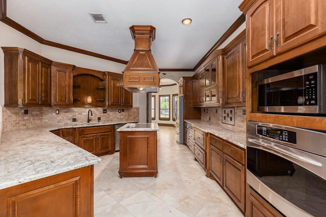 kitchen featuring sink, appliances with stainless steel finishes, tasteful backsplash, light stone countertops, and a kitchen island