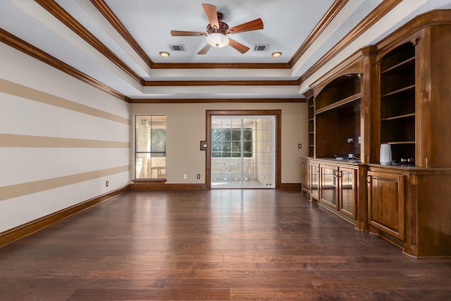 empty room featuring a raised ceiling, ornamental molding, dark hardwood / wood-style flooring, and built in shelves