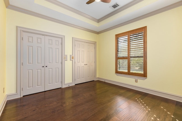 unfurnished bedroom featuring a raised ceiling, two closets, and ceiling fan