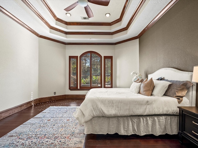 bedroom with crown molding, ceiling fan, a tray ceiling, and dark wood-type flooring