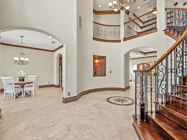 foyer featuring an inviting chandelier, ornamental molding, and a high ceiling