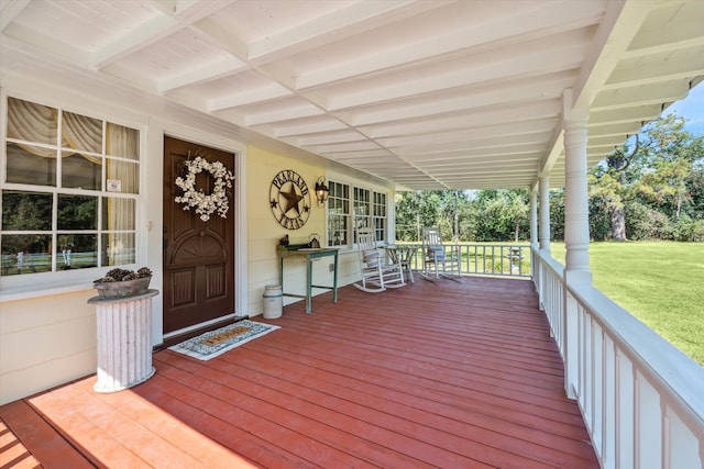 wooden deck featuring a lawn and covered porch