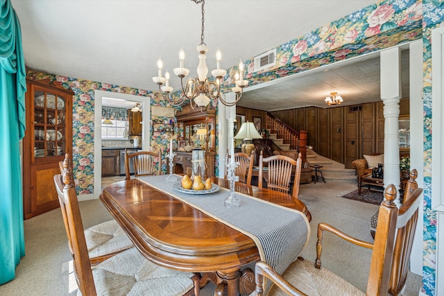 dining area featuring wood walls, light colored carpet, and an inviting chandelier