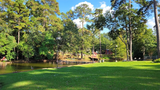 surrounding community with a water view and a lawn