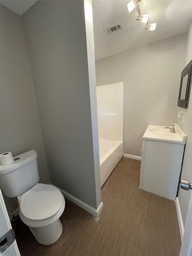 bathroom with vanity, a bathtub, hardwood / wood-style flooring, and toilet