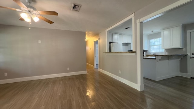 unfurnished living room featuring ceiling fan and dark hardwood / wood-style flooring