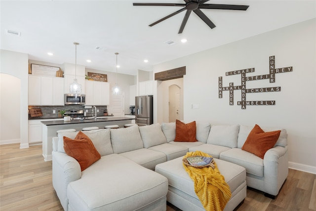 living room featuring light hardwood / wood-style flooring, ceiling fan, and sink