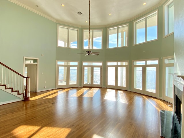 unfurnished living room featuring a healthy amount of sunlight, a towering ceiling, and ceiling fan