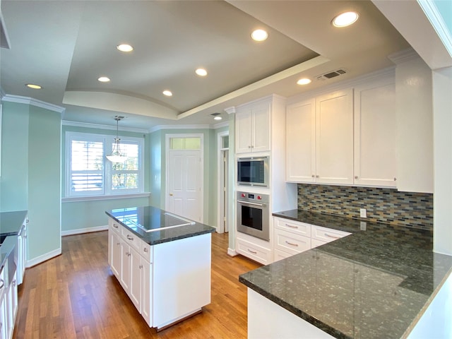 kitchen with stainless steel appliances, white cabinetry, light wood-type flooring, and a kitchen island